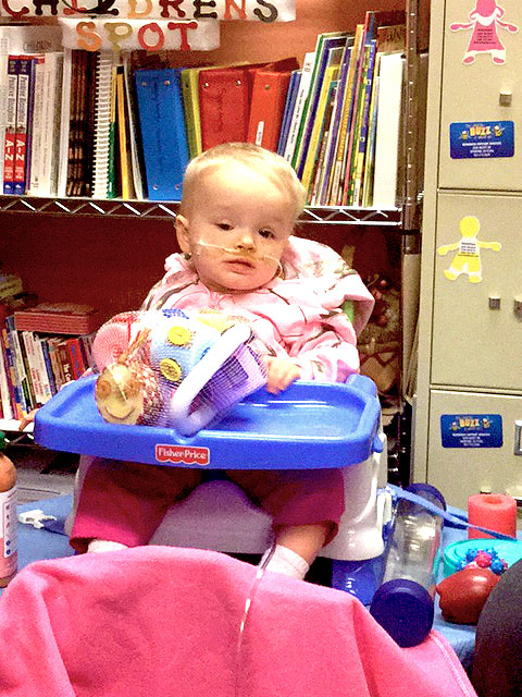 A child sitting in a high chair is learning by touching things with her fingers.